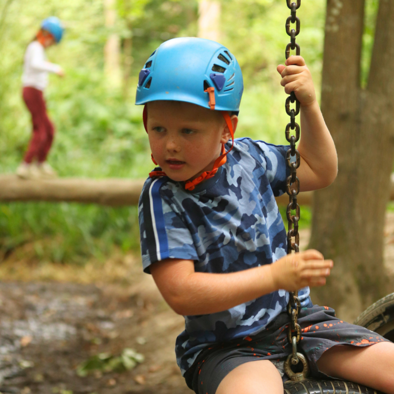 Young boy on tyre swing with safety hat.